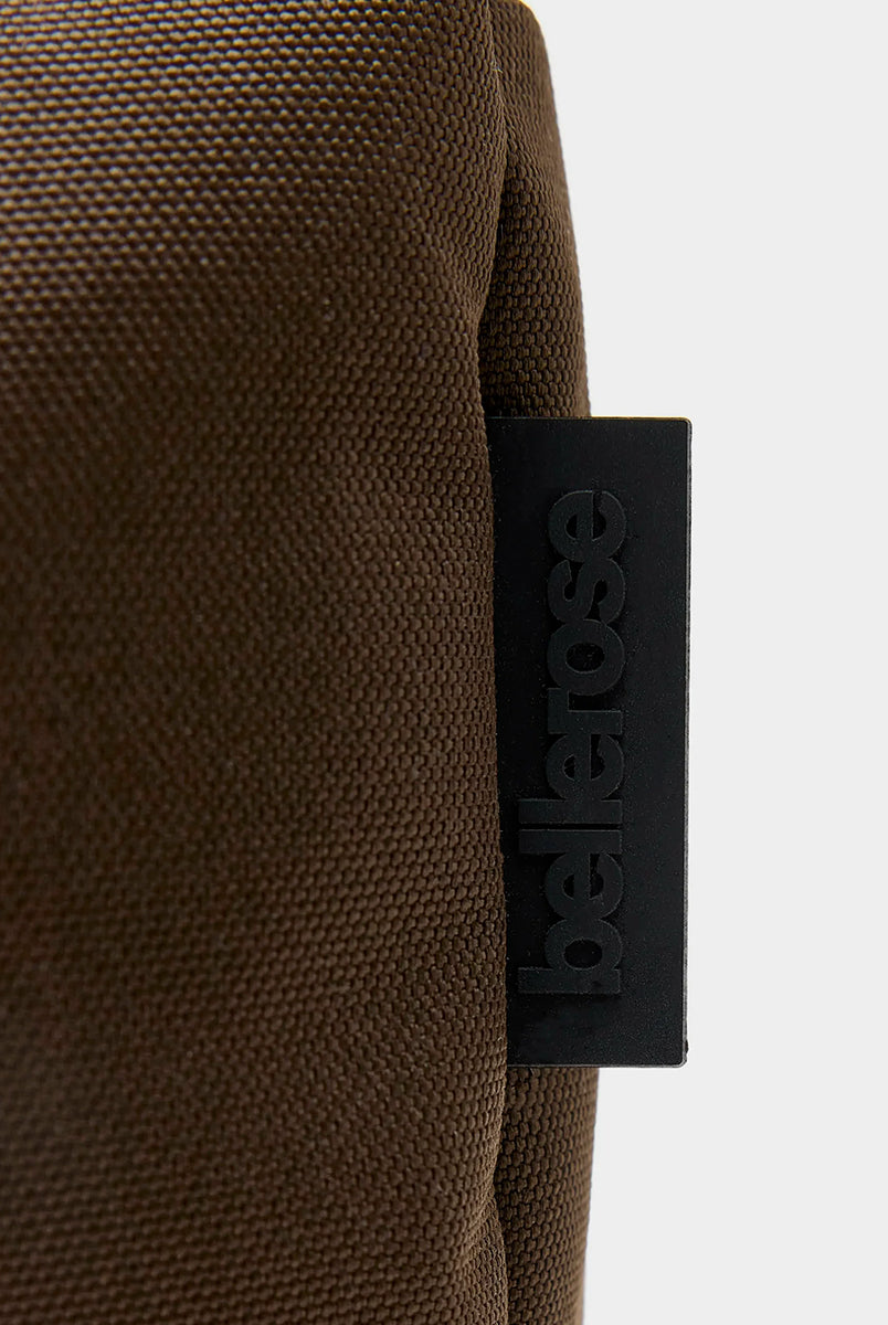 Zapinana na suwak torebka typu cross body Hobbes Dark Roast marki Bellerose z brązowego, matowego nylonu o fakturowanej powierzchni. Wyróżnia się prostokątnym kształtem, miękką konstrukcją oraz regulowanym paskiem w paski i silikonowym logo. 