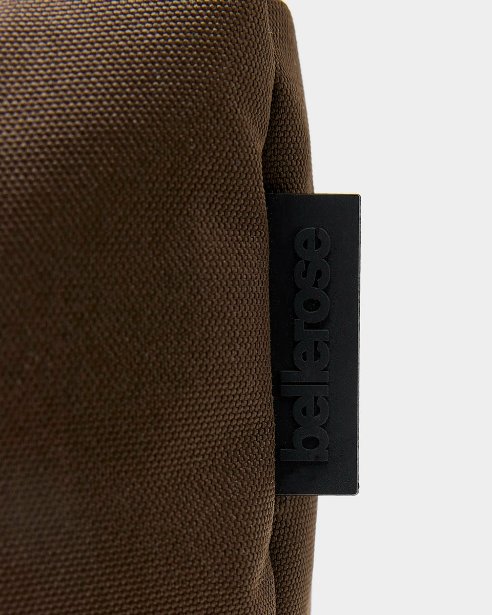 Zapinana na suwak torebka typu cross body Hobbes Dark Roast marki Bellerose z brązowego, matowego nylonu o fakturowanej powierzchni. Wyróżnia się prostokątnym kształtem, miękką konstrukcją oraz regulowanym paskiem w paski i silikonowym logo. 