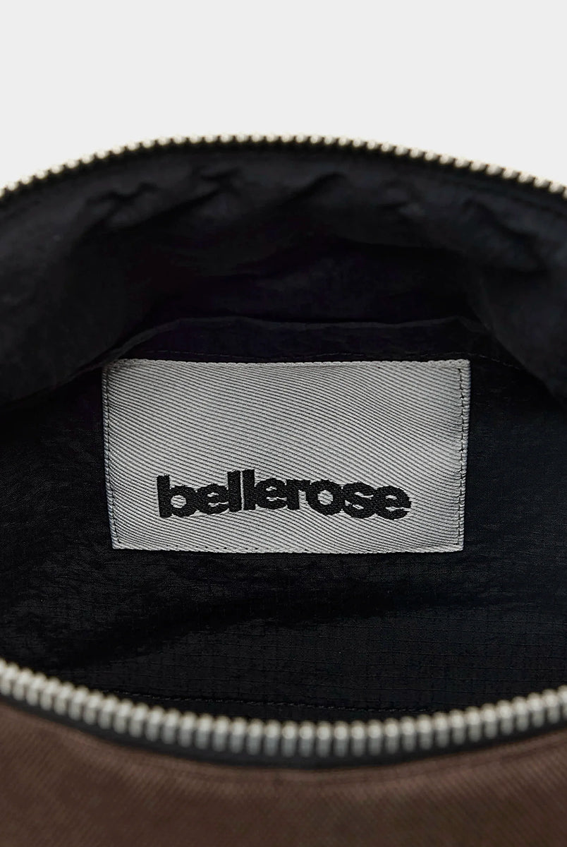 Zapinana na suwak torebka typu cross body Hobbes Dark Roast marki Bellerose z brązowego, matowego nylonu o fakturowanej powierzchni. Wyróżnia się prostokątnym kształtem, miękką konstrukcją oraz regulowanym paskiem w paski i silikonowym logo. 