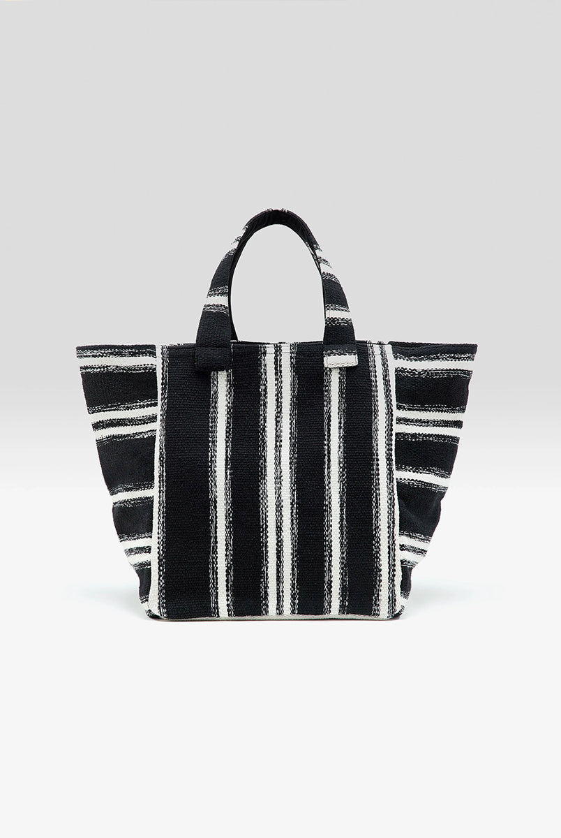 Gruba, tkana, bawełniana torba Ibox Stripe A marki Bellerose w czarno-białe paski. Bardzo pojemna w środku. Posiada solidne uchwyty, wewnętrzną kieszeń główną oraz mniejszą kieszeń z metką na imię. Na bocznym szwie widoczna jest niewielka etykieta z logo marki. Wykonana z grubej bawełny. 