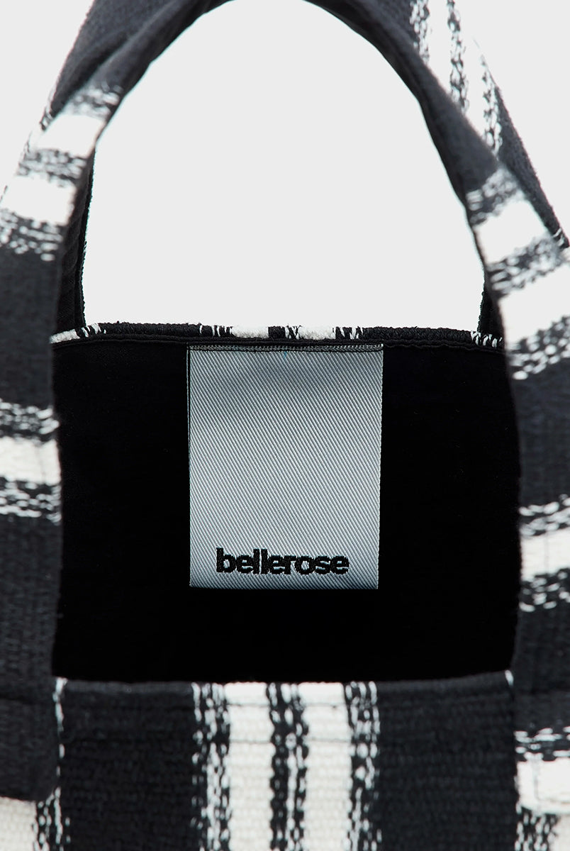 Gruba, tkana, bawełniana torba Ibox Stripe A marki Bellerose w czarno-białe paski. Bardzo pojemna w środku. Posiada solidne uchwyty, wewnętrzną kieszeń główną oraz mniejszą kieszeń z metką na imię. Na bocznym szwie widoczna jest niewielka etykieta z logo marki. Wykonana z grubej bawełny. 