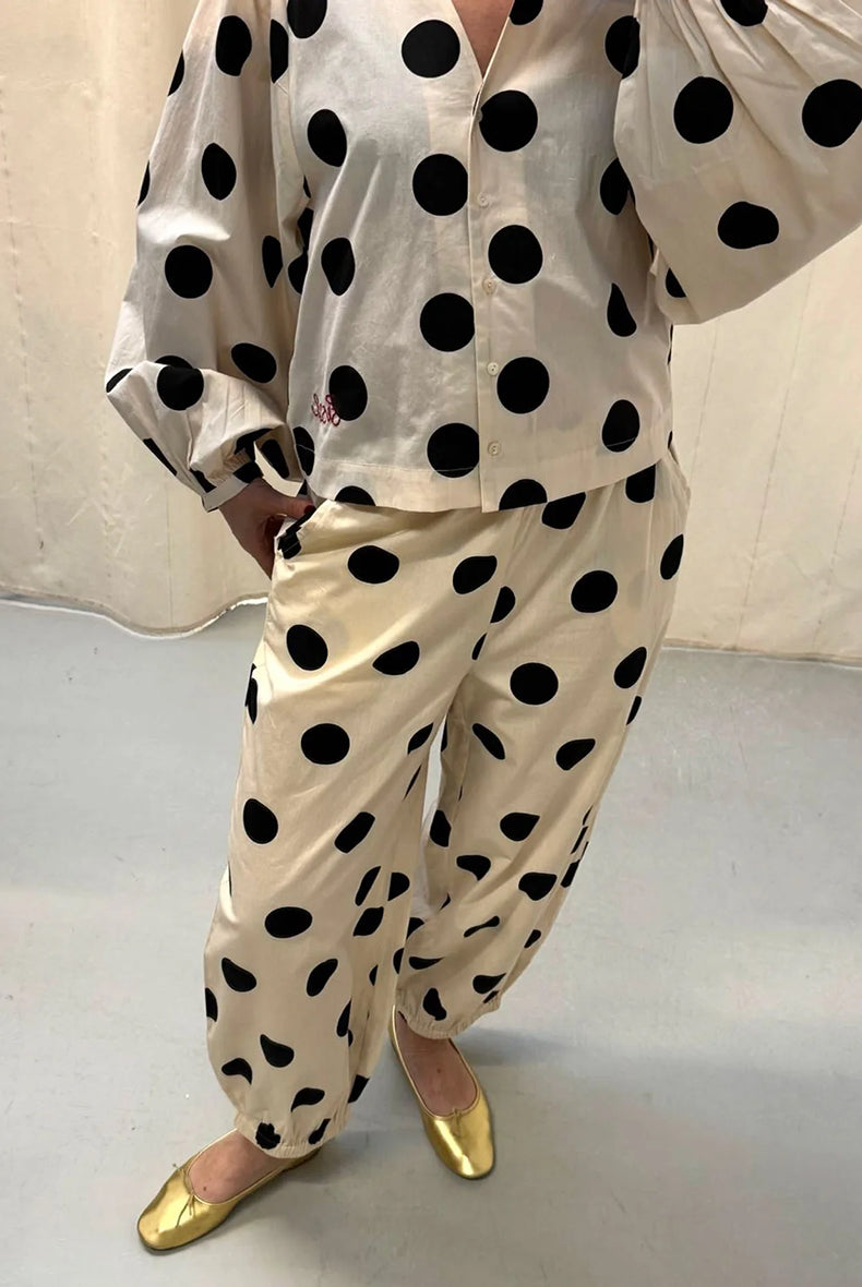 Luźne spodnie Iluna SISSEL EDELBO z żakardowej tkaniny z modnym wzorem polka dots. Posiadają szerokie, luźne nogawki zakończone wąskimi, elastycznymi ściągaczami. Spodnie mają elastyczną talię. Wykonane zostały z tkaniny pozyskanej z postprodukcji, co nadaje spodniom oryginalności i niepowtarzalności.
-Luźny fason
-Lekka tkanina w czarne grochy
-Ręcznie wykonane hafty
-Zamów spodnie w swoim normalnym rozmiarze