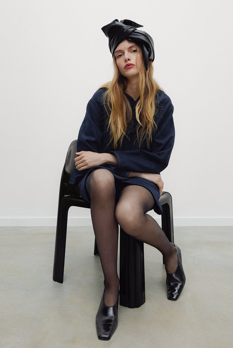 Elegancka, ciemnogranatowa, krótka kurtka Indie Black Iris o fasonie inspirowanym stylem wschodnim. Model ma prosty krój z okrągłym dekoltem bez kołnierzyka oraz długie rękawy o swobodnej linii. Charakterystycznym elementem są ozdobne, tekstylne zapięcia typu chińskiego, zwane węzełkami, które biegną wzdłuż przedniej plisy. Kurtka posiada również dwie duże, naszywane kieszenie oraz zaokrąglone doły po bokach, co nadaje jej miękki, nowoczesny wygląd. Wykonana z mieszanki z wełną.
-Inspirowana stylem wschodn
