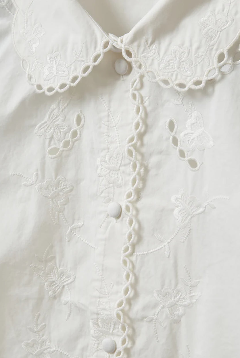Romantyczna, klasyczna koszula Kirsten Collar White marki The Garment z zaokrąglonym kołnierzykiem z haftem angielskim i ażurowymi wycięciami. Posiada bardzo wysokie, eleganckie mankiety. Na piersiach i wzdłuż linii guzików znajdują się delikatne, kwiatowe hafty. Zapinana na drobne guziki. Brzeg koszuli oraz listwa guzikowa wykończone są falistym brzegiem. Wykonana z bawełny organicznej.
-Ozdobiona haftem angielskim
-Faliste brzegi
-Zamów koszulę w swoim standardowym rozmiarze