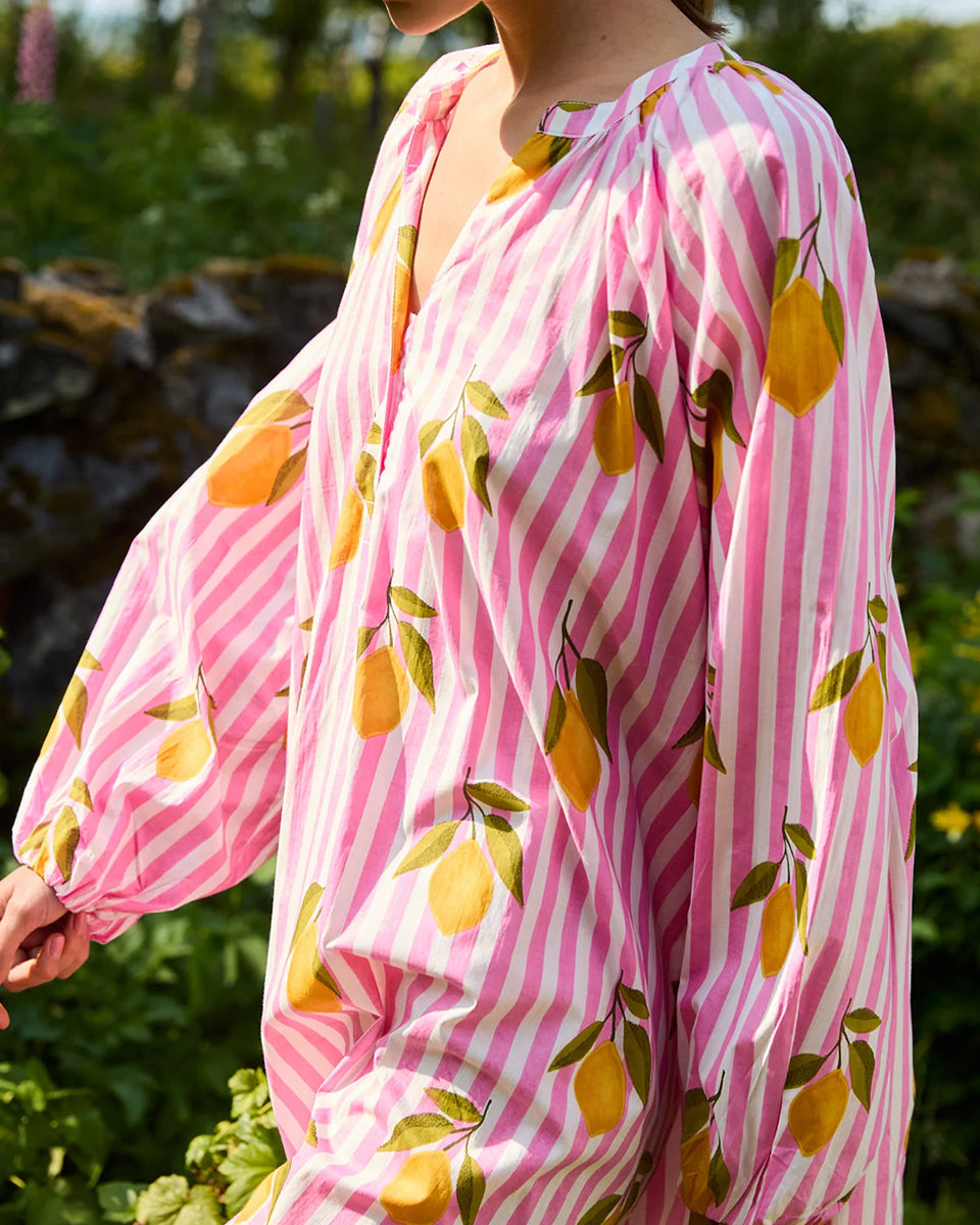 Luźna, szeroka sukienka Lara Pink Lemons SISSEL EDELBO z długimi, bufiastymi rękawami i dekoltem w serek z rozcięciem zapinanym na plisę i guziki z masy perłowej. Posiada również rozcięcia w bocznych szwach i marszczenia pod dekoltem. Ozdobiona jest pięknym, ręcznie wykonanym sitodrukiem. Wykonana w 100% z bawełny organicznej.
-Luźny krój oversize
-Ręcznie wykonany sitodruk
-100% bawełna organiczna
