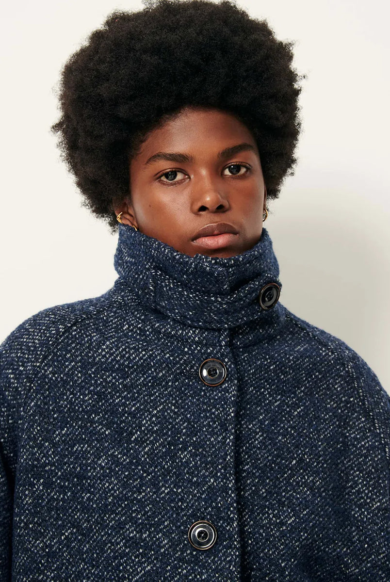 Luźny płaszcz wełniany typu bluza Lee Valley Denimwool marki Sessun wykonany z miękkiej, trójkolorowej tkaniny o splocie koszykowym, z efektem melanżowym. Posiada wysoki kołnierz, kieszenie oraz długie, raglanowe rękawy. Zapinany jest na duże guziki.
