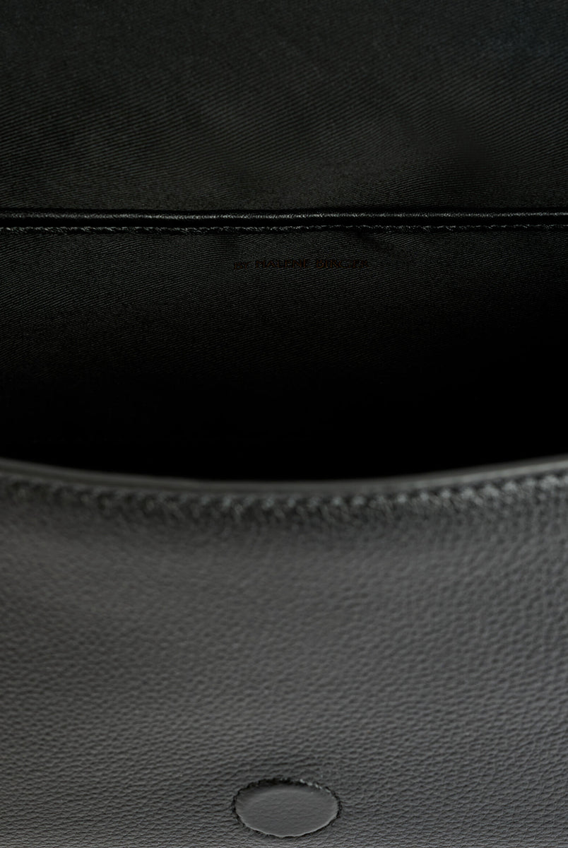 Minimalistyczna, elegancka torebka Lellie Black By Malene Birger o prostokątnym kształcie z lekko zaokrąglonymi bokami. Zapinana na zatrzask magnetyczny. Posiada krótki, szeroki pasek na ramię, który ozdobiony jest złotymi elementami. Na środku klapy umieszczono metalowy emblemat marki w kolorze złotym. W środku znajduje się mała kieszonka na drobiazgi, a całość wykończona jest gładką podszewką. Wykonana w 100% ze skóry. 