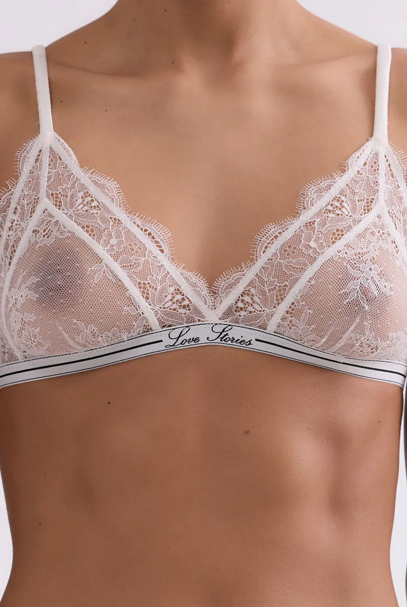 Delikatny, miękki stanik z trójkątnymi miseczkami Love Lace Love Stories. Wykonany z białej, koronkowej tkaniny. Stanik posiada cienką gumę pod biustem z logo marki oraz regulowane, marszczone ramiączka. Zapinany na plecach za pomocą haftek.