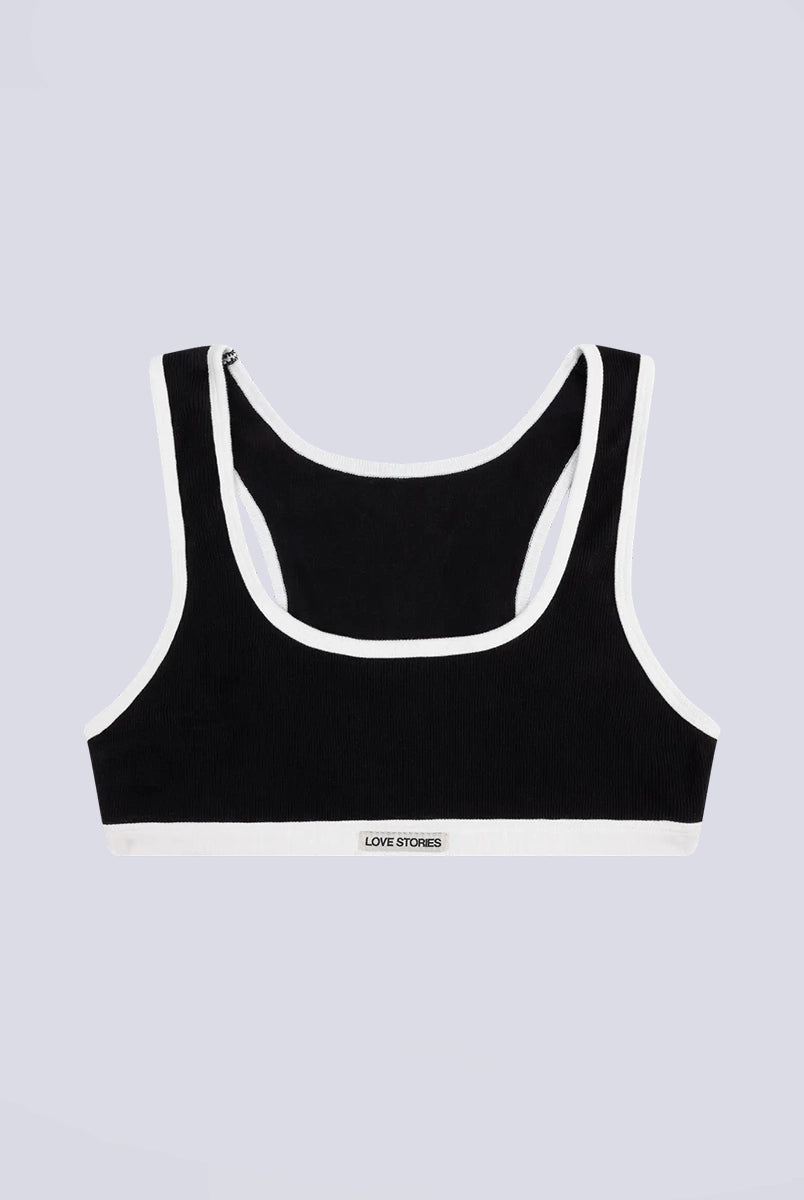 Miękki sportowy stanik top Rika Love Love Stories na grubych ramiączkach. Wykonany z miękkiej tkaniny z prążkowaną fakturą i białą, grubą lamówką. Na gumie pod biustem posiada niewielką naszywkę z logo marki. 