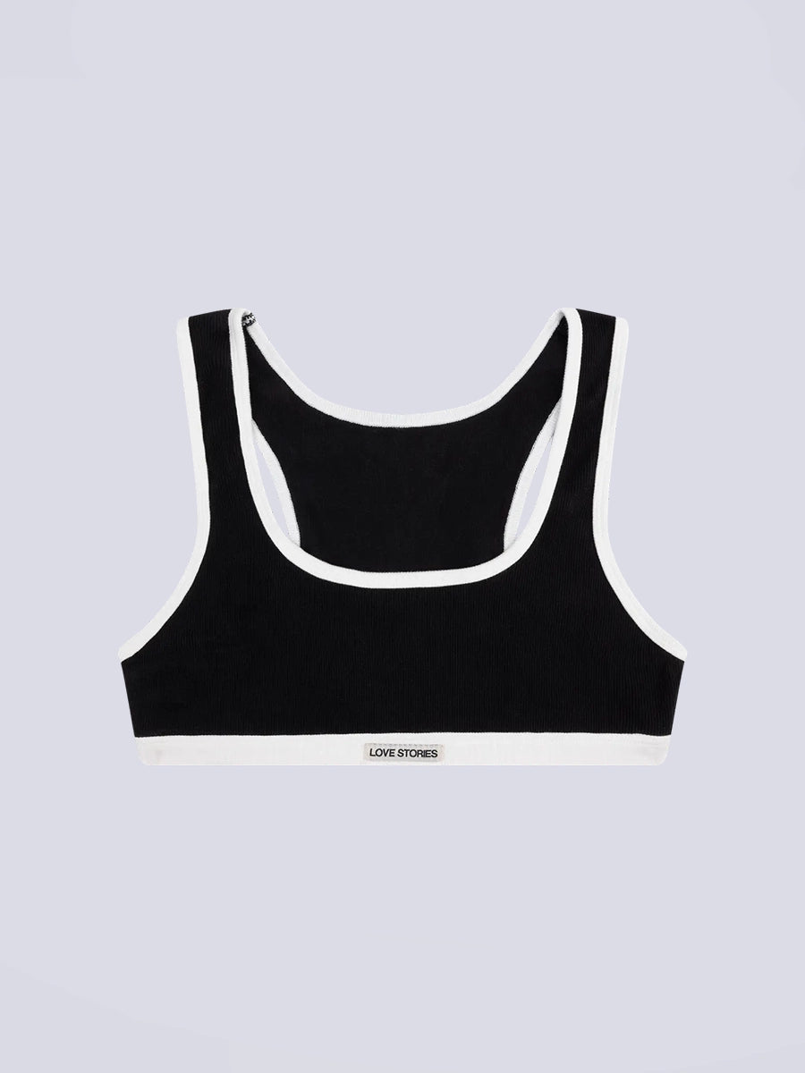 Miękki sportowy stanik top Rika Love Love Stories na grubych ramiączkach. Wykonany z miękkiej tkaniny z prążkowaną fakturą i białą, grubą lamówką. Na gumie pod biustem posiada niewielką naszywkę z logo marki. 