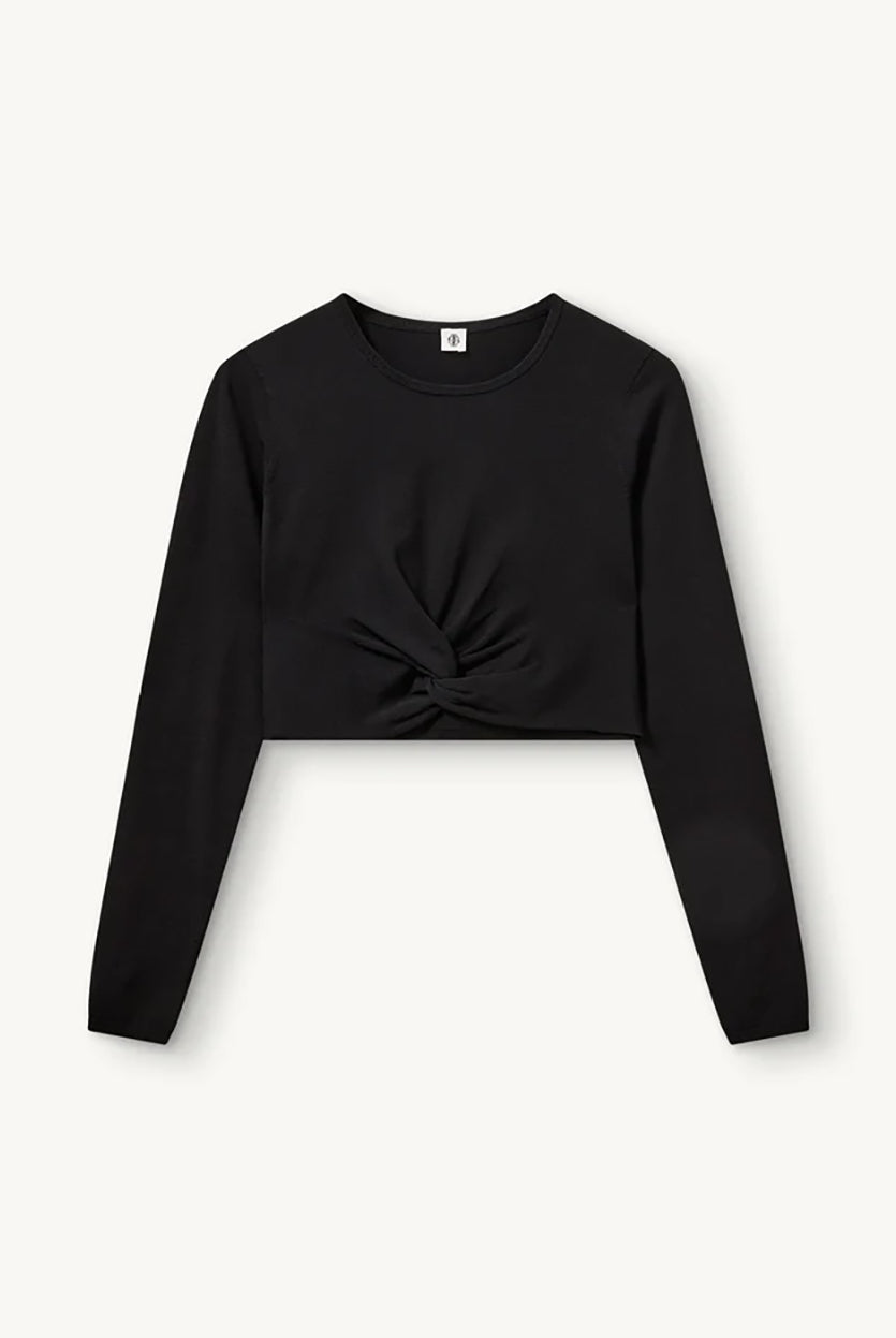 Czarny, dopasowany top Madison Black marki The Garment o minimalistycznym, wyrazistym kroju. Ma okrągły, zabudowany dekolt i długie rękawy. U dołu materiał jest zebrany i związany w supeł, co tworzy delikatne marszczenie i skróconą długość odsłaniającą brzuch. Wykonany z miękkiej, przylegającej do ciała tkaniny.
-Dopasowany krój
-Skrócona długość
-Zamów top w swoim standardowym rozmiarze