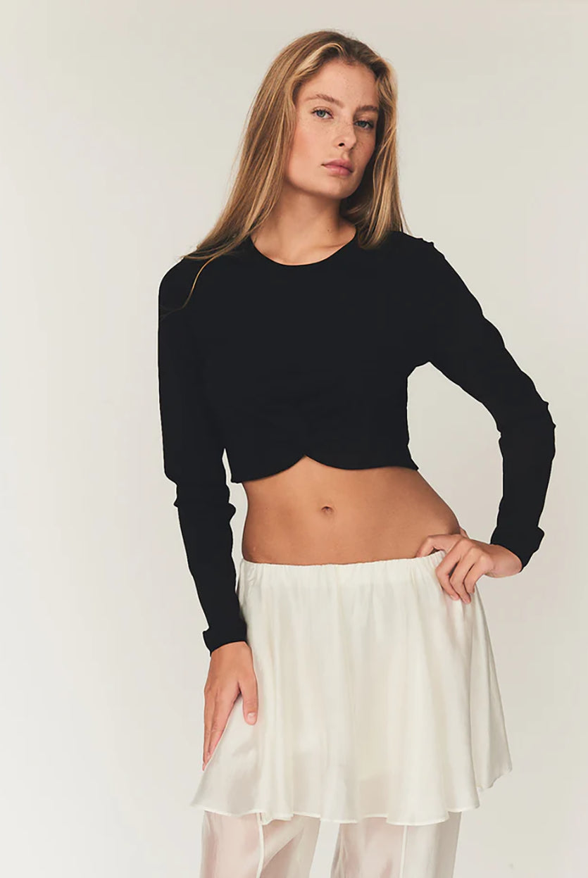 Czarny, dopasowany top Madison Black marki The Garment o minimalistycznym, wyrazistym kroju. Ma okrągły, zabudowany dekolt i długie rękawy. U dołu materiał jest zebrany i związany w supeł, co tworzy delikatne marszczenie i skróconą długość odsłaniającą brzuch. Wykonany z miękkiej, przylegającej do ciała tkaniny.
-Dopasowany krój
-Skrócona długość
-Zamów top w swoim standardowym rozmiarze