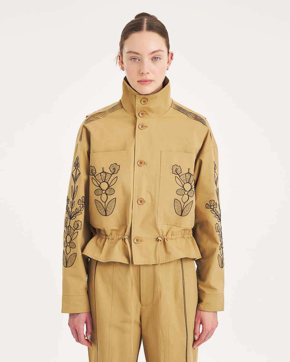 Krótka, strukturalna kurtka Maria Beige Antik Batik o nowoczesnym, nieco geometrycznym kroju. Posiada charakterystyczną, bardzo wysoką stójkę zapinaną na guziki. Regulowana w pasie za pomocą ściągacza ze sznurkami, co tworzy efekt delikatnej baskinki/falbany. Z przodu na kieszeniach oraz na rękawach znajdują się hafty z motywami roślinnymi i kwiatowymi. Dodatkowe, drobne, haftowane przeszycia ozdabiają również linię ramion. Zapinana na guziki.
-Krótki, nowoczesny fason
-Hafty z motywami roślinnymi i