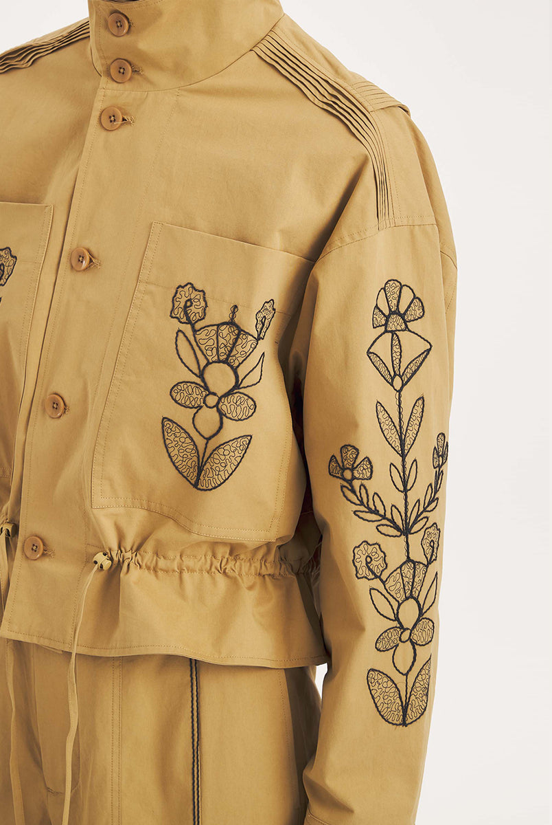 Krótka, strukturalna kurtka Maria Beige Antik Batik o nowoczesnym, nieco geometrycznym kroju. Posiada charakterystyczną, bardzo wysoką stójkę zapinaną na guziki. Regulowana w pasie za pomocą ściągacza ze sznurkami, co tworzy efekt delikatnej baskinki/falbany. Z przodu na kieszeniach oraz na rękawach znajdują się hafty z motywami roślinnymi i kwiatowymi. Dodatkowe, drobne, haftowane przeszycia ozdabiają również linię ramion. Zapinana na guziki.
-Krótki, nowoczesny fason
-Hafty z motywami roślinnymi i