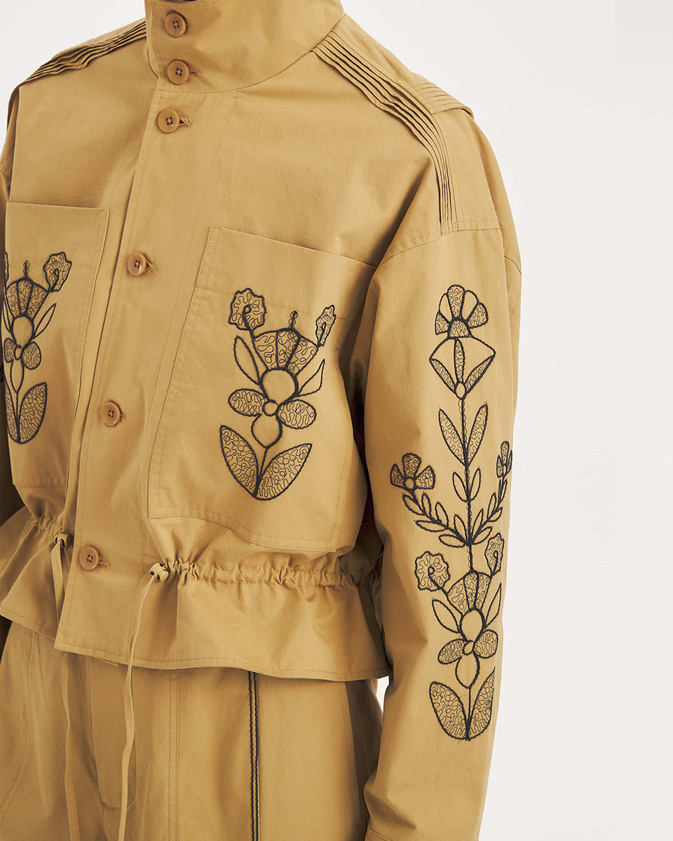 Krótka, strukturalna kurtka Maria Beige Antik Batik o nowoczesnym, nieco geometrycznym kroju. Posiada charakterystyczną, bardzo wysoką stójkę zapinaną na guziki. Regulowana w pasie za pomocą ściągacza ze sznurkami, co tworzy efekt delikatnej baskinki/falbany. Z przodu na kieszeniach oraz na rękawach znajdują się hafty z motywami roślinnymi i kwiatowymi. Dodatkowe, drobne, haftowane przeszycia ozdabiają również linię ramion. Zapinana na guziki.
-Krótki, nowoczesny fason
-Hafty z motywami roślinnymi i