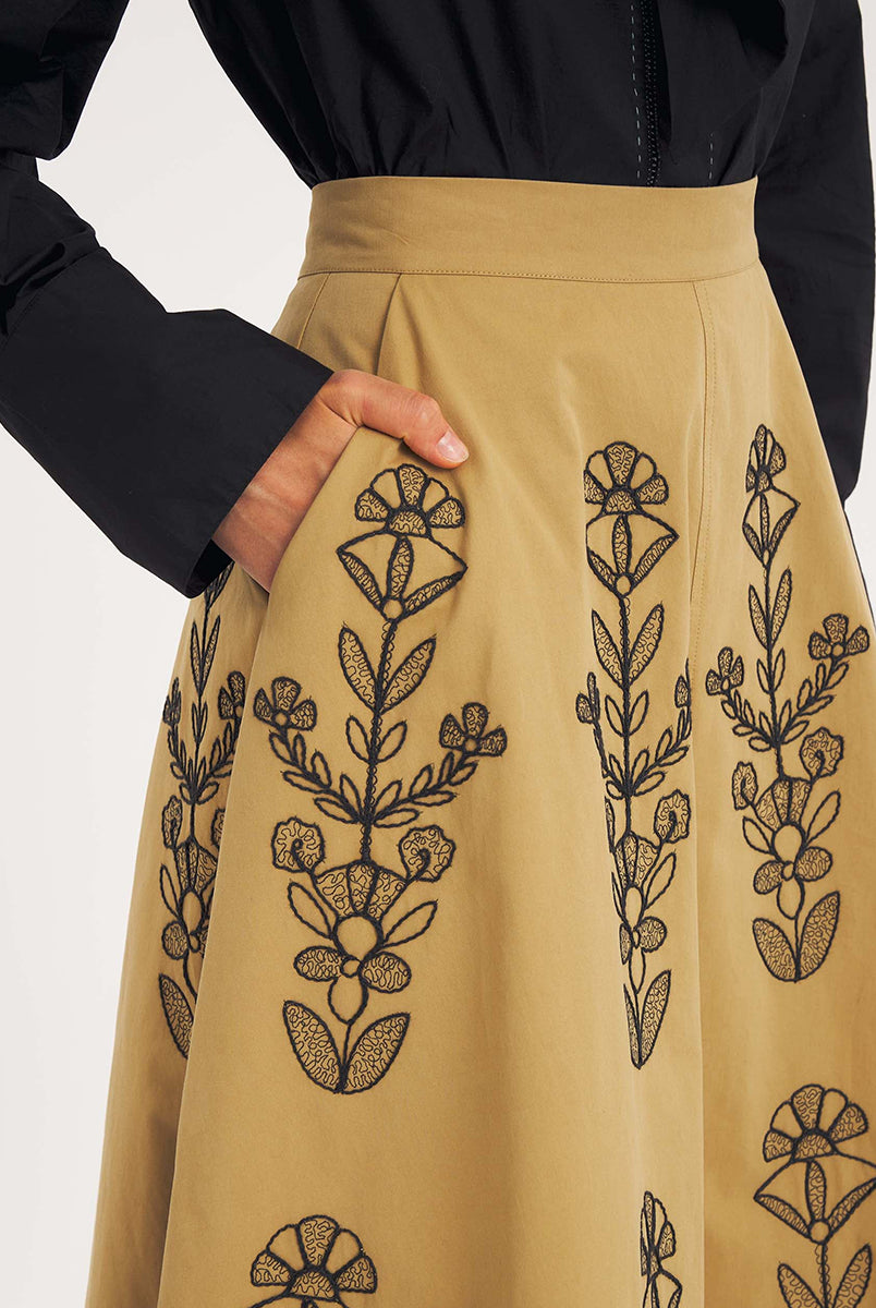 Rozkloszowana, trapezowa spódnica Maria Beige marki Antik Batik o klasycznej długości midi, sięgającej do połowy łydki. Ma wysoką, gładką talię z wyraźnie zaznaczonym, szerokim pasem. Głównym elementem dekoracyjnym są duże, pionowe hafty roślinne i kwiatowe w ciemnym kolorze. Haft układa się symetrycznie, w pionowe rzędy, co optycznie wydłuża sylwetkę i nadaje całości tradycyjny, rzemieślniczy charakter.
-Długość midi
-Wysoki stan
-Ozdobne hafty kwiatowe i roślinne
-Zamów spódnicę w swoim standard