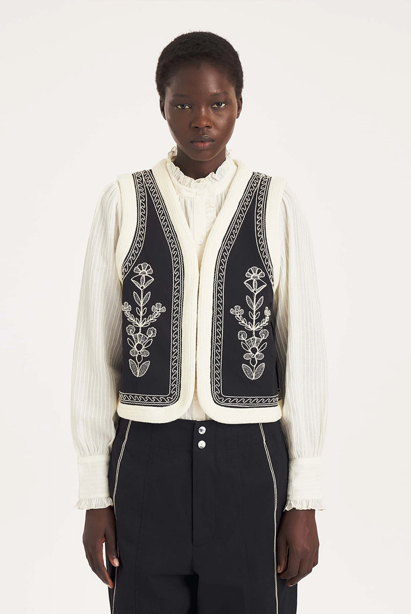 Krótka kamizelka Maria Black marki Antik Batik o wyraźnym, etnicznym charakterze nawiązującym do stylu boho-chic. Jest to fason sięgający do linii bioder, z otwartym przodem, bez widocznego zapięcia. Przód kamizelki zdobi bogaty, symetryczny haft w kontrastującym kolorze. Wszystkie krawędzie zostały obszyte ozdobną, wzorzystą taśmą z geometrycznym haftem. Zestaw ją z ulubionymi spodniami oraz luźną, białą koszulą z bufiastymi rękawami i wysoką stójką.
-Krótki fason
-Symetryczne hafty
-Zamów kamizelkę w s