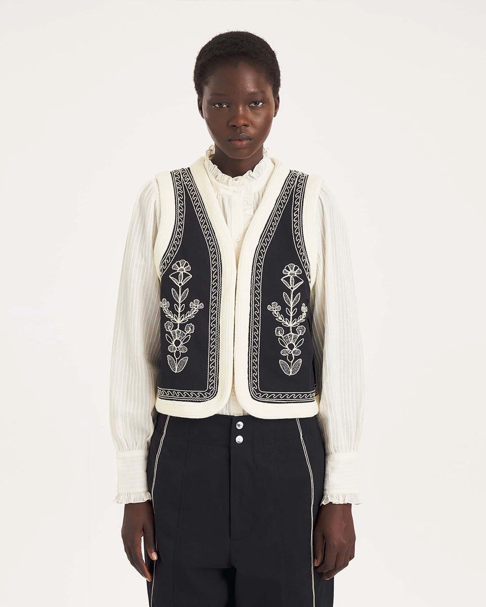 Krótka kamizelka Maria Black marki Antik Batik o wyraźnym, etnicznym charakterze nawiązującym do stylu boho-chic. Jest to fason sięgający do linii bioder, z otwartym przodem, bez widocznego zapięcia. Przód kamizelki zdobi bogaty, symetryczny haft w kontrastującym kolorze. Wszystkie krawędzie zostały obszyte ozdobną, wzorzystą taśmą z geometrycznym haftem. Zestaw ją z ulubionymi spodniami oraz luźną, białą koszulą z bufiastymi rękawami i wysoką stójką.
-Krótki fason
-Symetryczne hafty
-Zamów kamizelkę w s