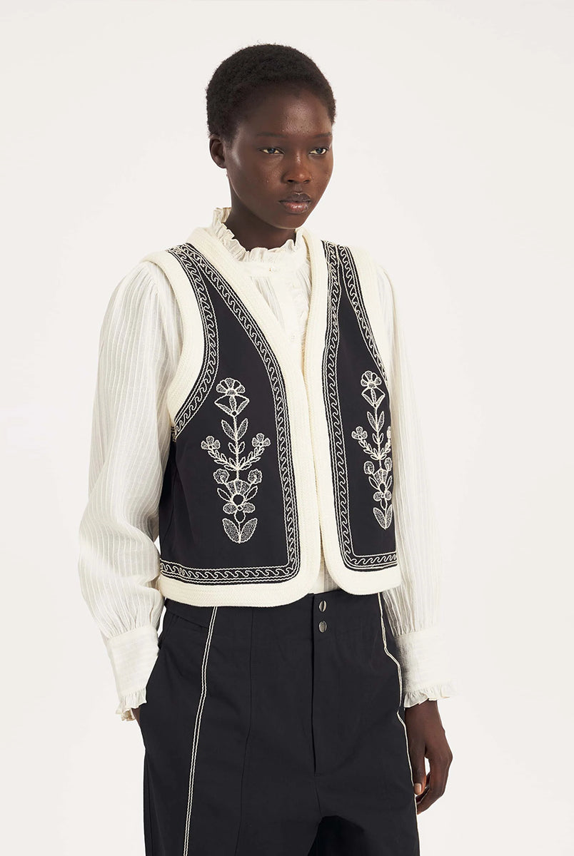 Krótka kamizelka Maria Black marki Antik Batik o wyraźnym, etnicznym charakterze nawiązującym do stylu boho-chic. Jest to fason sięgający do linii bioder, z otwartym przodem, bez widocznego zapięcia. Przód kamizelki zdobi bogaty, symetryczny haft w kontrastującym kolorze. Wszystkie krawędzie zostały obszyte ozdobną, wzorzystą taśmą z geometrycznym haftem. Zestaw ją z ulubionymi spodniami oraz luźną, białą koszulą z bufiastymi rękawami i wysoką stójką.
-Krótki fason
-Symetryczne hafty
-Zamów kamizelkę w s