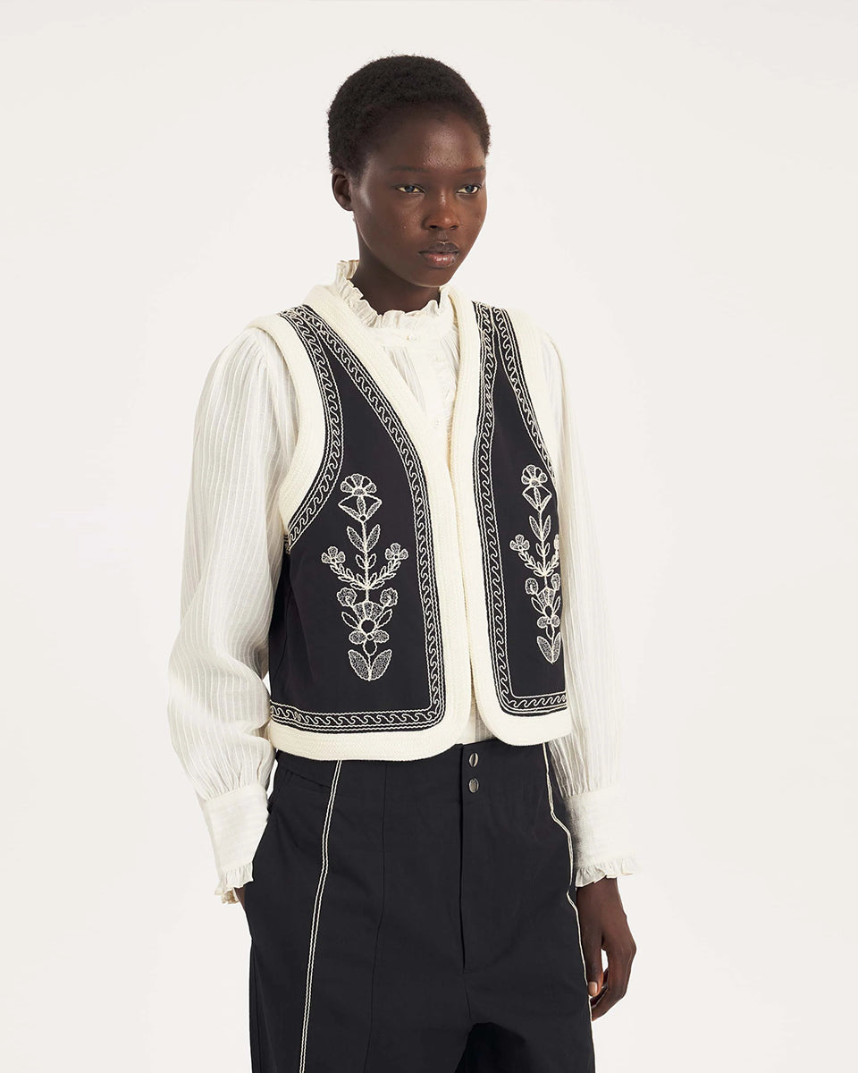 Krótka kamizelka Maria Black marki Antik Batik o wyraźnym, etnicznym charakterze nawiązującym do stylu boho-chic. Jest to fason sięgający do linii bioder, z otwartym przodem, bez widocznego zapięcia. Przód kamizelki zdobi bogaty, symetryczny haft w kontrastującym kolorze. Wszystkie krawędzie zostały obszyte ozdobną, wzorzystą taśmą z geometrycznym haftem. Zestaw ją z ulubionymi spodniami oraz luźną, białą koszulą z bufiastymi rękawami i wysoką stójką.
-Krótki fason
-Symetryczne hafty
-Zamów kamizelkę w s