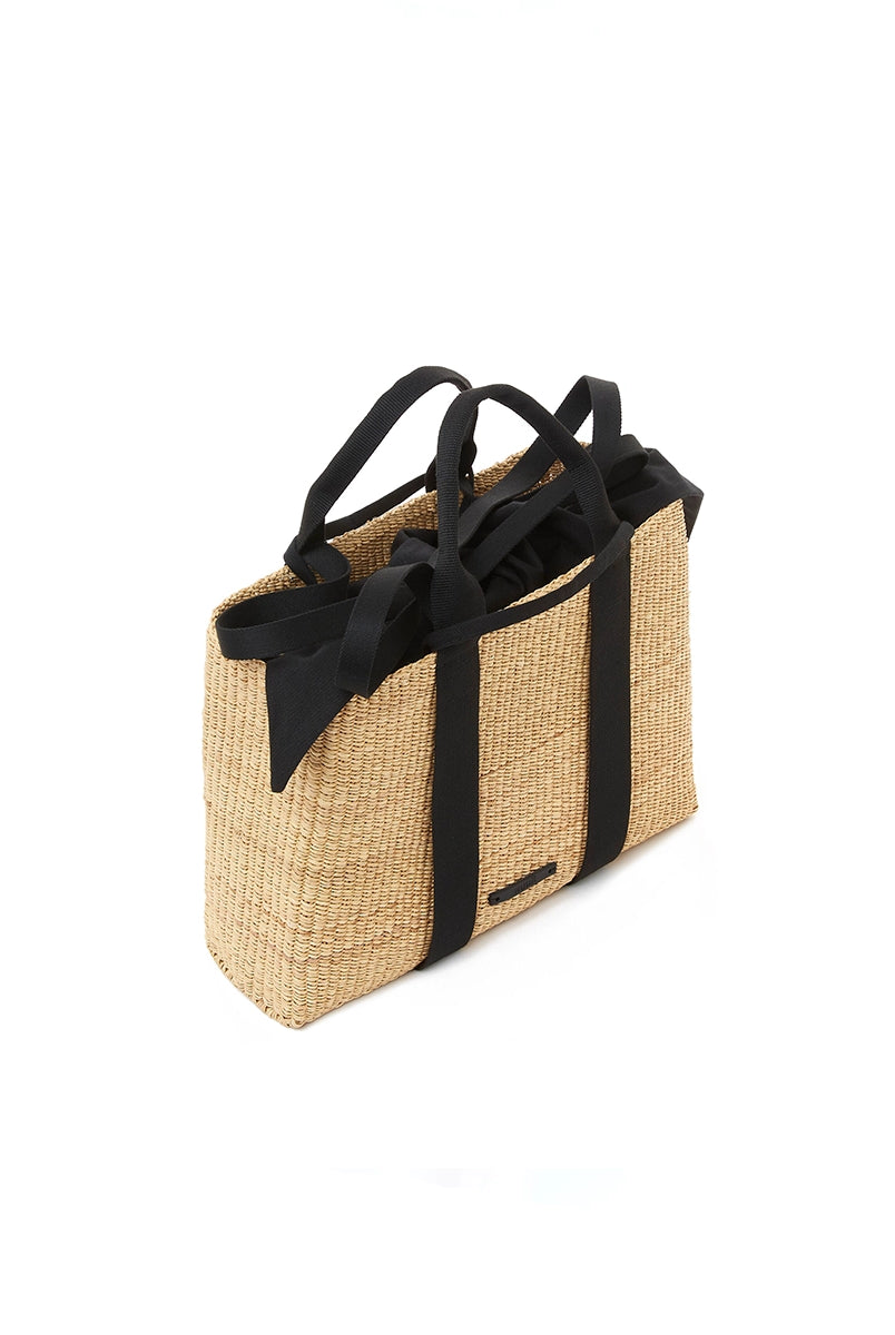 Średniej wielkości, ręcznie pleciony kosz JEROME - NATURAL x BLACK HDL x BLACK COTTON francuskiej marki Muun. Posiada prostokątny kształt, dwie mocne, plecione materiałowe rączki w kolorze ciemnozielonym do wygodnego trzymania w dłoni i zawieszenia na ramieniu. Wewnątrz koszyka znajduje się wiązana, wyciągana bawełniana, czarna torebka