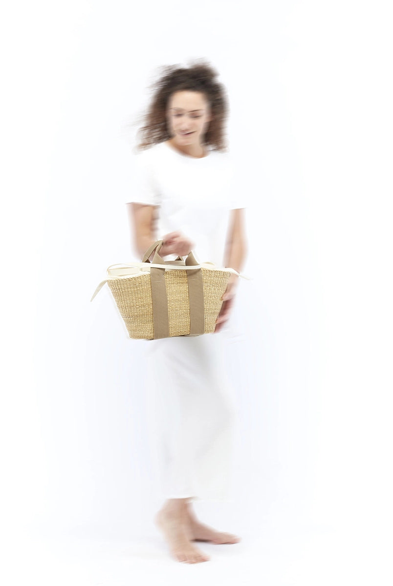 Średniej wielkości, ręcznie pleciony kosz GEORGE - NATURAL x BEIGE HDL x NATURAL LINEN francuskiej marki Muun. Posiada trapezowy kształt, dwie mocne, materiałowe rączki do wygodnego trzymania w dłoni oraz długi, cienki pasek do zawieszenia na ramieniu.
