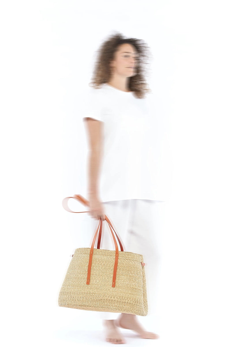 Duży, ręcznie pleciony kosz LAURA - NATURAL x TAN HDL x ECRU COTTON francuskiej marki Muun. Posiada trapezowy kształt, dwie mocne, skórzane rączki w kolorze do wygodnego trzymania w dłoni i zawieszenia na ramieniu. Wewnątrz koszyka znajduje się wiązana, wyciągana bawełniana, kremowa torebka.