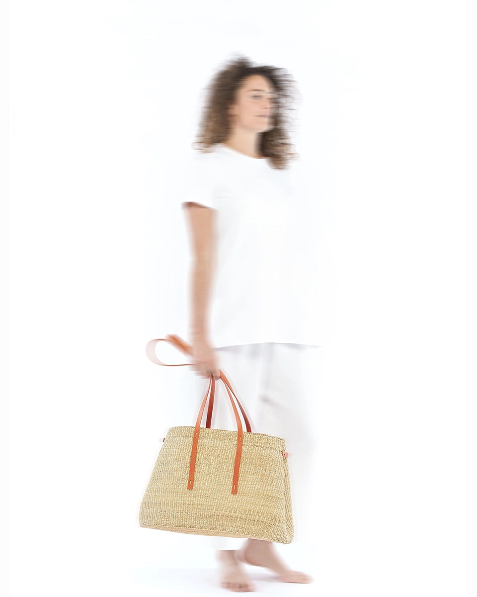 Duży, ręcznie pleciony kosz LAURA - NATURAL x TAN HDL x ECRU COTTON francuskiej marki Muun. Posiada trapezowy kształt, dwie mocne, skórzane rączki w kolorze do wygodnego trzymania w dłoni i zawieszenia na ramieniu. Wewnątrz koszyka znajduje się wiązana, wyciągana bawełniana, kremowa torebka.