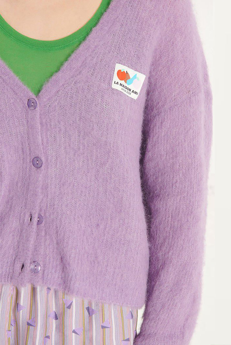 Oversizowy, miękki kardigan Nenybay Violet marki American Vintage z długim rękawem i dekoltem w serek. Zapinany na guziki. Posiada naszywkę z logo na piersi. Zakończony ściągaczami. Wykonany z lekkiej dzianiny z alpaką. Noś go samodzielnie lub połącz z innymi elementami garderoby, aby stworzyć warstwowy, codzienny look. 