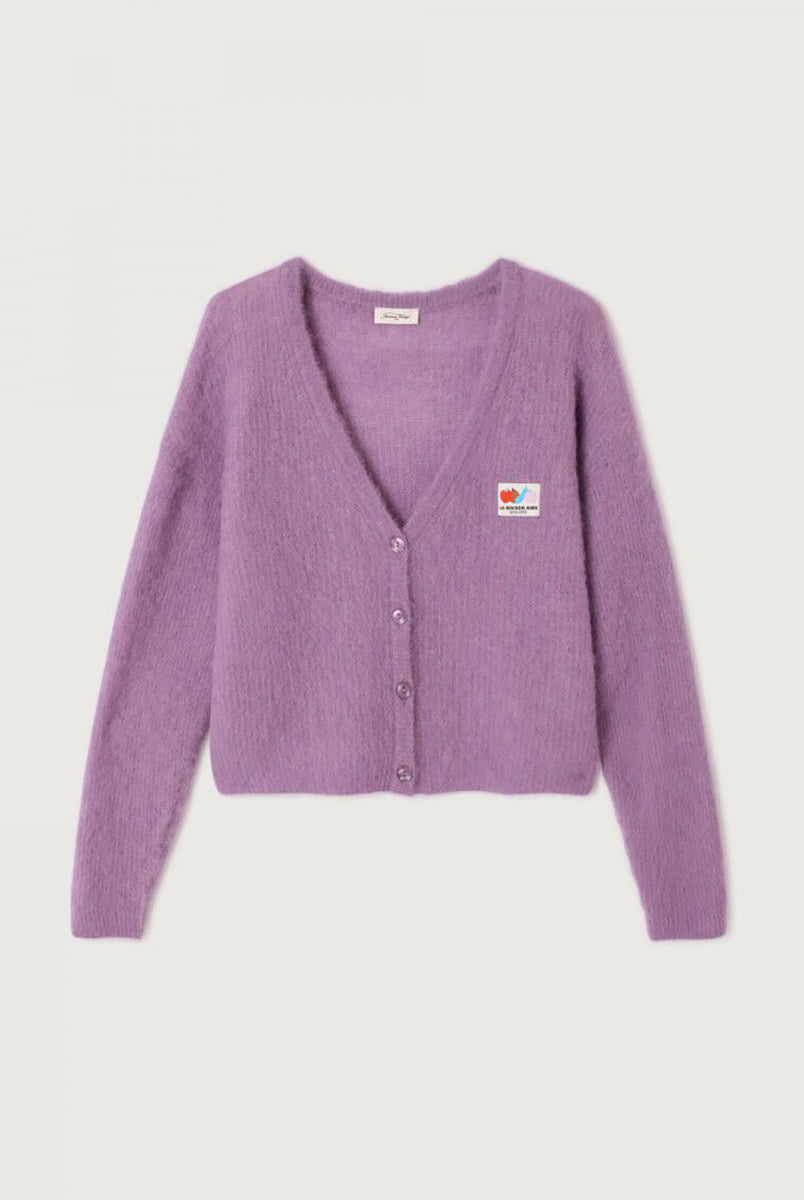 Oversizowy, miękki kardigan Nenybay Violet marki American Vintage z długim rękawem i dekoltem w serek. Zapinany na guziki. Posiada naszywkę z logo na piersi. Zakończony ściągaczami. Wykonany z lekkiej dzianiny z alpaką. Noś go samodzielnie lub połącz z innymi elementami garderoby, aby stworzyć warstwowy, codzienny look. 