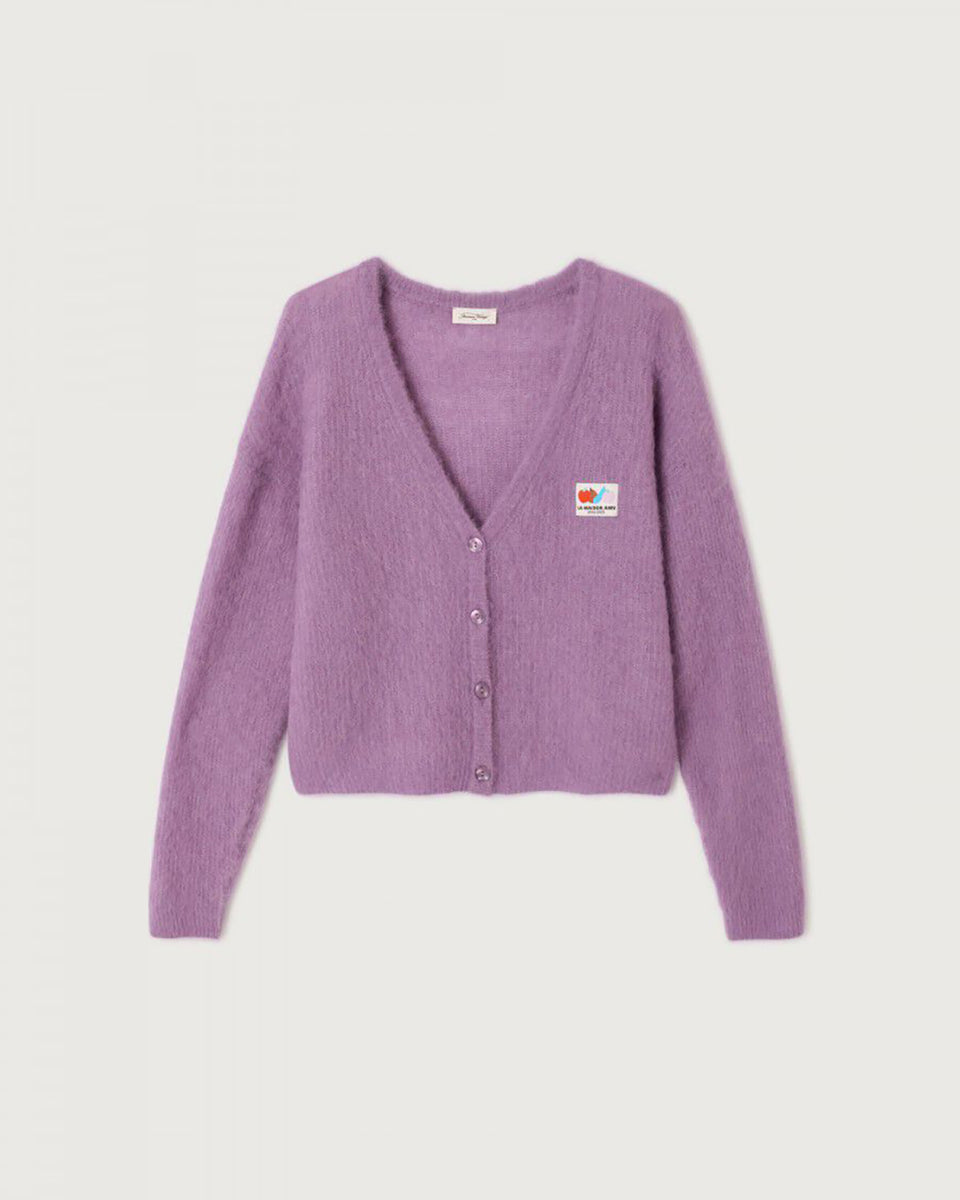 Oversizowy, miękki kardigan Nenybay Violet marki American Vintage z długim rękawem i dekoltem w serek. Zapinany na guziki. Posiada naszywkę z logo na piersi. Zakończony ściągaczami. Wykonany z lekkiej dzianiny z alpaką. Noś go samodzielnie lub połącz z innymi elementami garderoby, aby stworzyć warstwowy, codzienny look. 
