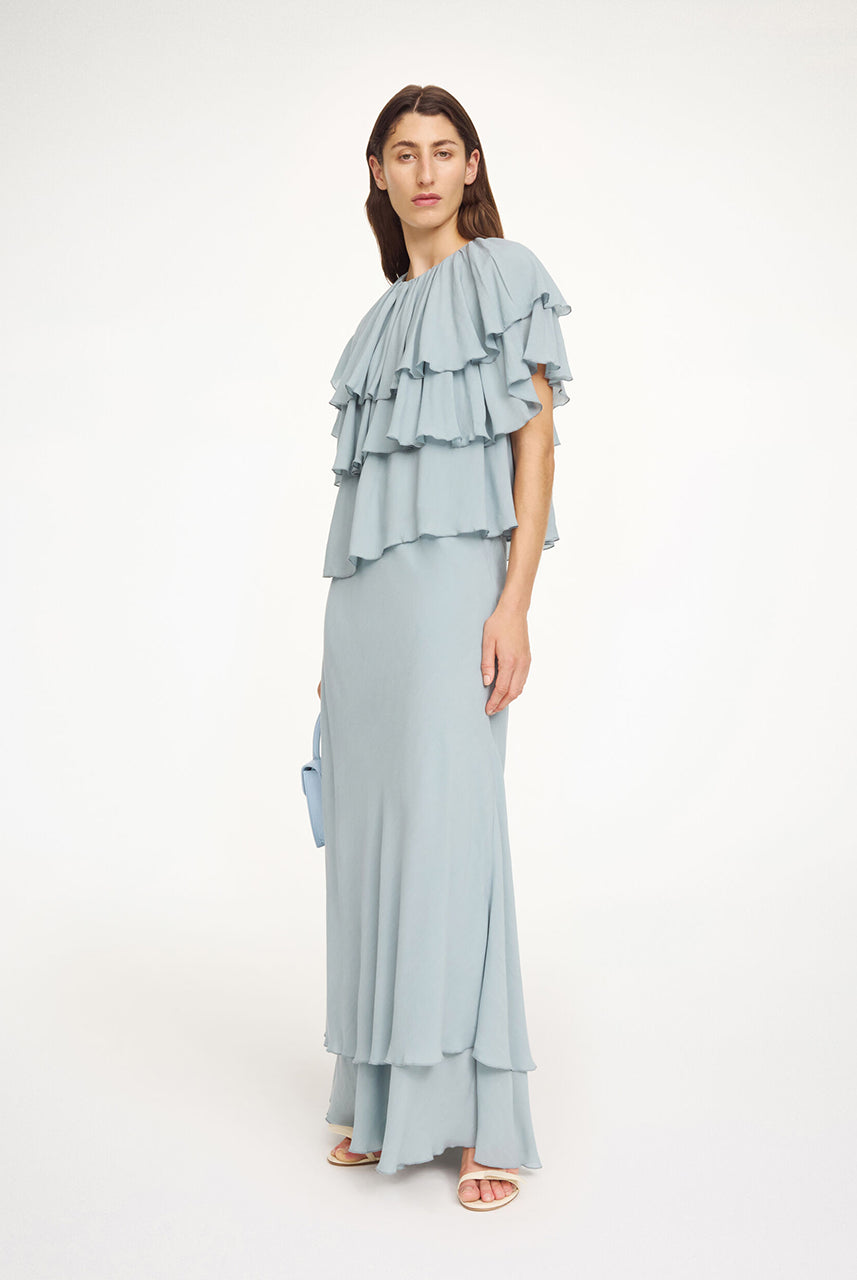 Luźny, błękitny top Nina Arona Blue By Malene Birger z okrągłym dekoltem i wiązaniem z tyłu. Składa się z kilku, półprzezroczystych warstw. Pierwsza falbana opada na ramiona, tworząc efekt 'rękawa skrzydełka'. Wykonany z wiskozy.
-Luźny, swobodny fason
-Bez rękawów
-Zamów w swoim standardowym rozmiarze 