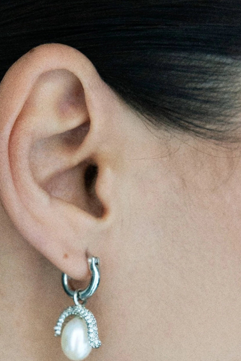 Efektowne, wiszące kolczyki PEARL OCTOPUSS.Y BABY PARIS SILVER z angielskim zapięciem. Złożone z grubego kółka i ściąganej zawieszki z dużą, naturalną perłą i połyskującym elementem wysadzanym drobnymi kryształami.