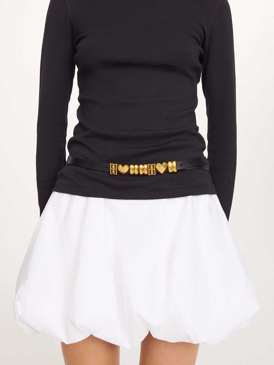 Skórzany, cienki pasek Ounlas Black By Malene Birger ze złotymi akcentami w kształcie serduszek i monogramów. Posiada regulowane zapięcie na klamrę. Wykonany z ziarnistej skóry. Idealny do sukienki i spodni stanem. 