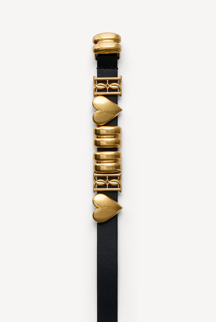 Skórzany, cienki pasek Ounlas Black By Malene Birger ze złotymi akcentami w kształcie serduszek i monogramów. Posiada regulowane zapięcie na klamrę. Wykonany z ziarnistej skóry. Idealny do sukienki i spodni stanem. 