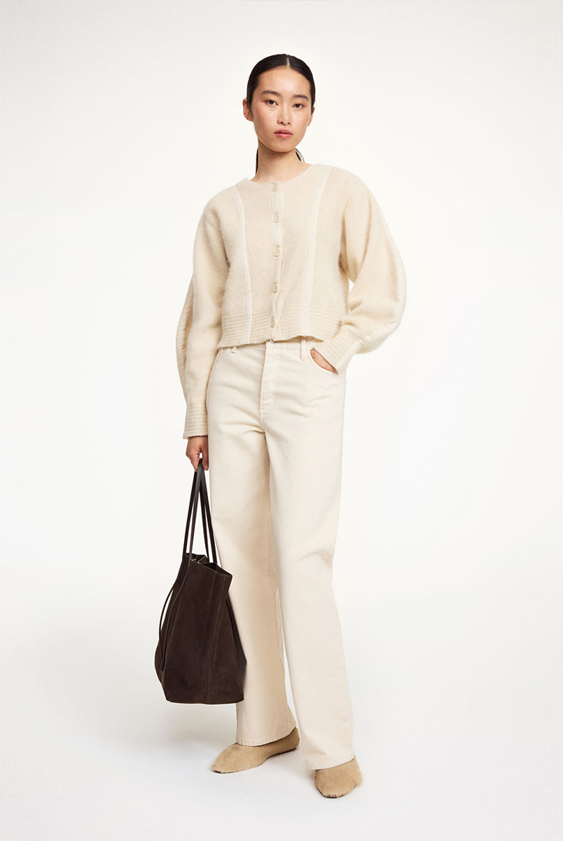 Krótki, luźny kardigan Pernille Cream By Malene Birger z okrągłym dekoltem, obniżoną linią ramion i szerokimi, balonowymi rękawami ze ściągaczami. Posiada pionowe, ozdobne sploty na długości i rękawach, dzięki czemu sylwetka wydaje się bardziej wysmuklona. Zapinany z przodu na guziki. Wykonany z miękkiej mieszanki moheru.
-Zamów w swoim standardowym rozmiarze