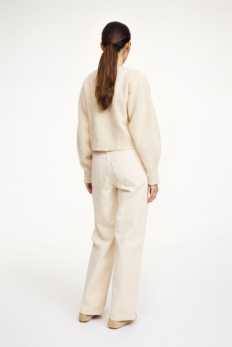 Krótki, luźny kardigan Pernille Cream By Malene Birger z okrągłym dekoltem, obniżoną linią ramion i szerokimi, balonowymi rękawami ze ściągaczami. Posiada pionowe, ozdobne sploty na długości i rękawach, dzięki czemu sylwetka wydaje się bardziej wysmuklona. Zapinany z przodu na guziki. Wykonany z miękkiej mieszanki moheru.
-Zamów w swoim standardowym rozmiarze