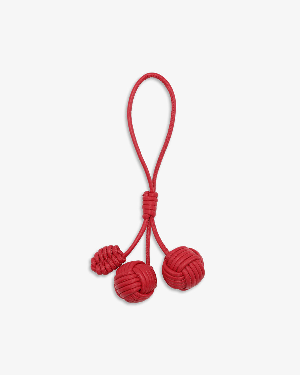 Uroczy breloczek Pine Cone SUI AVA składający się z plecionych kulek połączonych sznurkiem z pętelką, który bez z łatwością przymocujesz do torebki lub kluczy.
