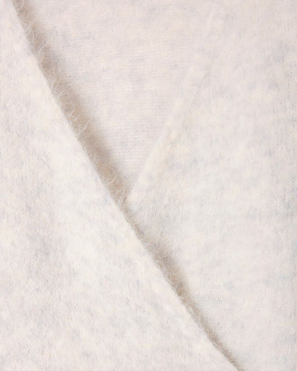 Miękki, krótki sweter NUN18 Polar Melange marki American Vintage z długimi rękawami i głębokim, skrzyżowanym kołnierzem. Wykończony ściągaczami. Wykonany z ciepłej dzianiny z alpaką. Jego kulisty kształt i kopertowy dekolt sprawiają, że jest to kobiecy, a zarazem wygodny element garderoby. Noś go z jeansami, spódnicą lub legginsami. 