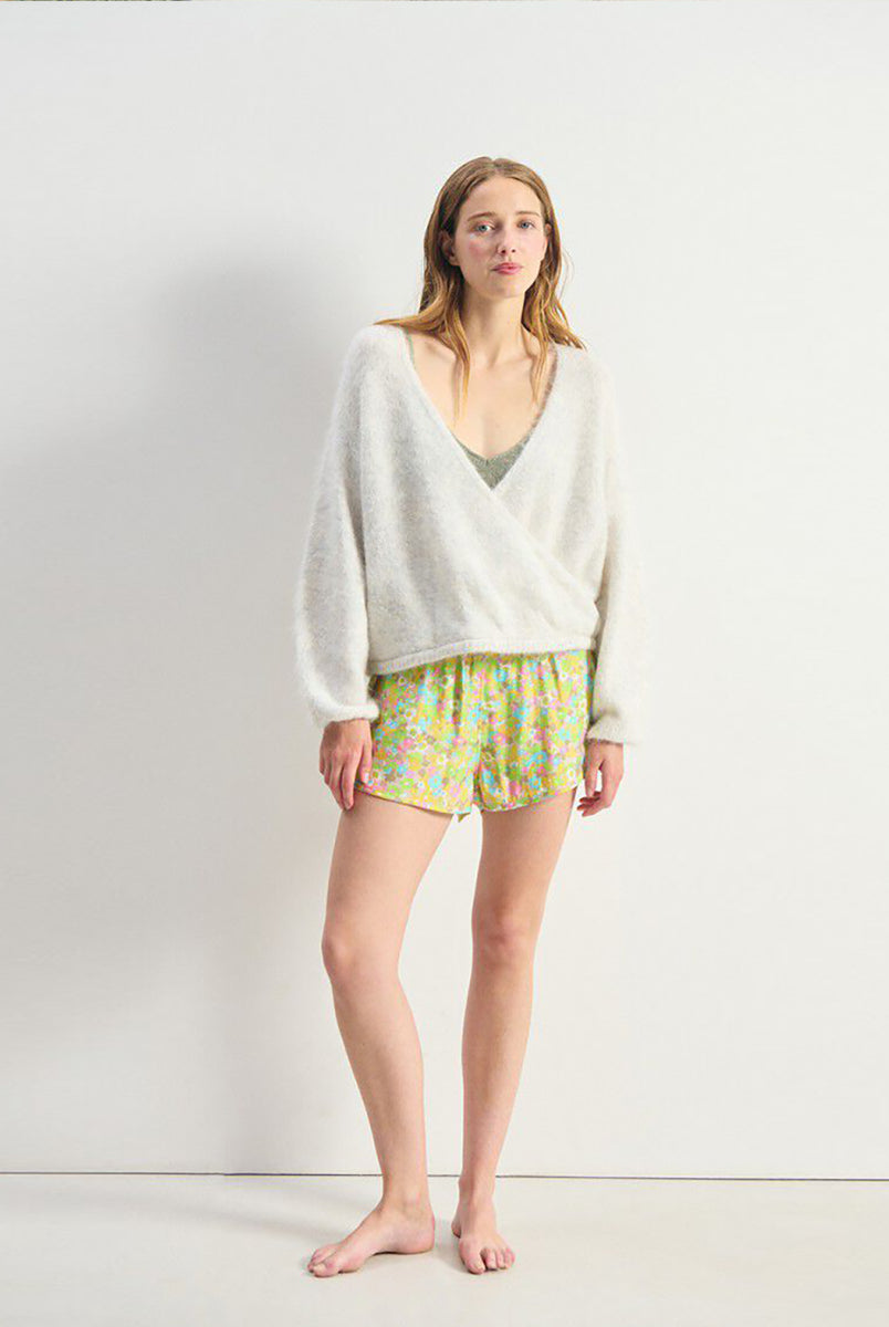 Miękki, krótki sweter NUN18 Polar Melange marki American Vintage z długimi rękawami i głębokim, skrzyżowanym kołnierzem. Wykończony ściągaczami. Wykonany z ciepłej dzianiny z alpaką. Jego kulisty kształt i kopertowy dekolt sprawiają, że jest to kobiecy, a zarazem wygodny element garderoby. Noś go z jeansami, spódnicą lub legginsami. 