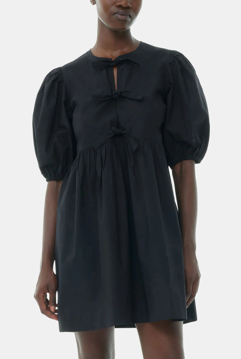 Luźna, czarna sukienka 9005 Poplin Mini Dress Black marki GANNI z okrągłym dekoltem i krótkimi, bufiastymi rękawami, które kończą się nad łokciem. Wiązana z przodu za pomocą sznurków. Odcięta wysoko w talii i rozkloszowana w dół. Wykonana z bawełny organicznej.
-Luźny fason
-100% bawełna organiczna
-Zamów w swoim standardowym rozmiarze