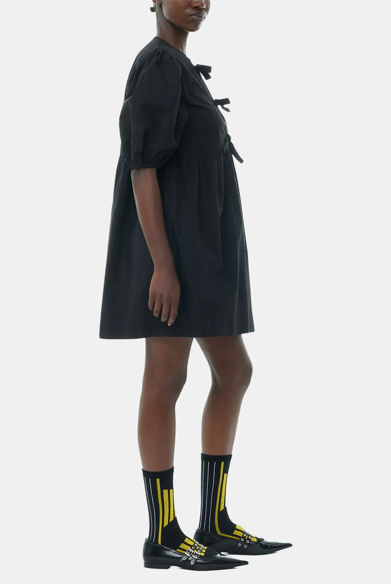 Luźna, czarna sukienka 9005 Poplin Mini Dress Black marki GANNI z okrągłym dekoltem i krótkimi, bufiastymi rękawami, które kończą się nad łokciem. Wiązana z przodu za pomocą sznurków. Odcięta wysoko w talii i rozkloszowana w dół. Wykonana z bawełny organicznej.
-Luźny fason
-100% bawełna organiczna
-Zamów w swoim standardowym rozmiarze
