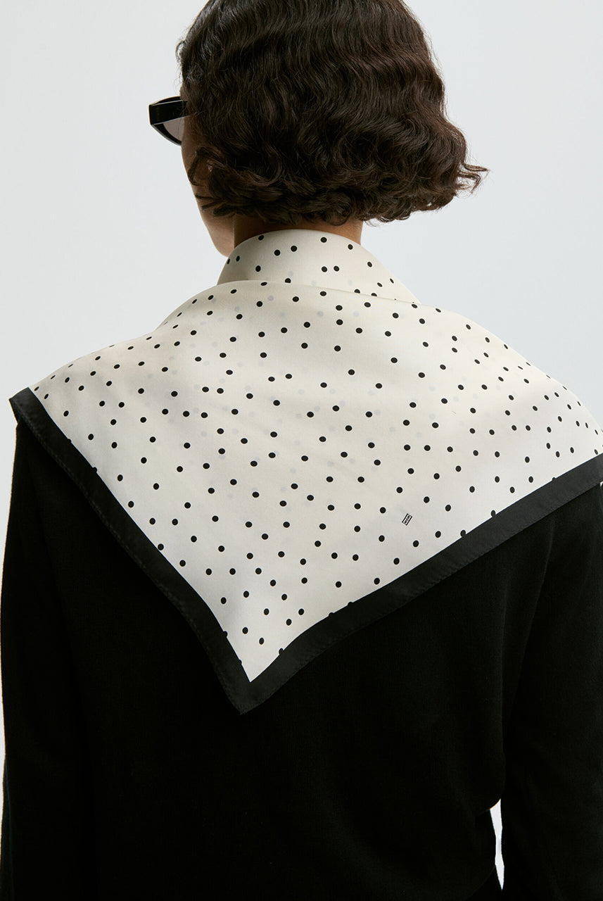 Klasyczna, piękna chusta Poula Black By Malene Birger w ponadczasowy wzór polka dots i kontrastową krawędzią. Wykonana z luksusowego jedwabiu. Zawiąż ją na szyi, nadgarstku lub rączce torebki.