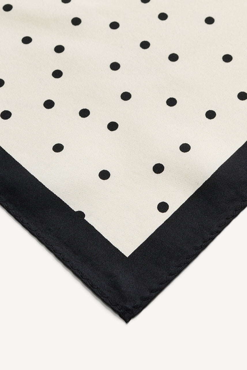 Klasyczna, piękna chusta Poula Black By Malene Birger w ponadczasowy wzór polka dots i kontrastową krawędzią. Wykonana z luksusowego jedwabiu. Zawiąż ją na szyi, nadgarstku lub rączce torebki.
