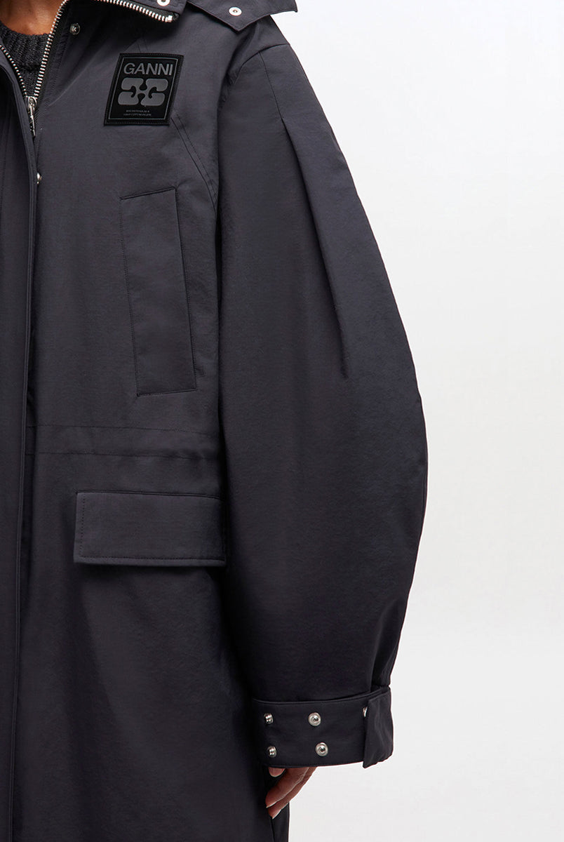 Luźny, prosty płaszcz typu parka 1012 Ganni Phantom o długości do kolan, z kapturem i mankietami. Posiada ściągacz w pasie i u dołu. Ma cztery kieszenie z przodu oraz kieszeń wewnętrzną. Nad lewą piersią znajduje się niewielka naszywka z logo marki. Zapinany za dwustronny zamek i srebrne, zatrzaskowe guziki. 