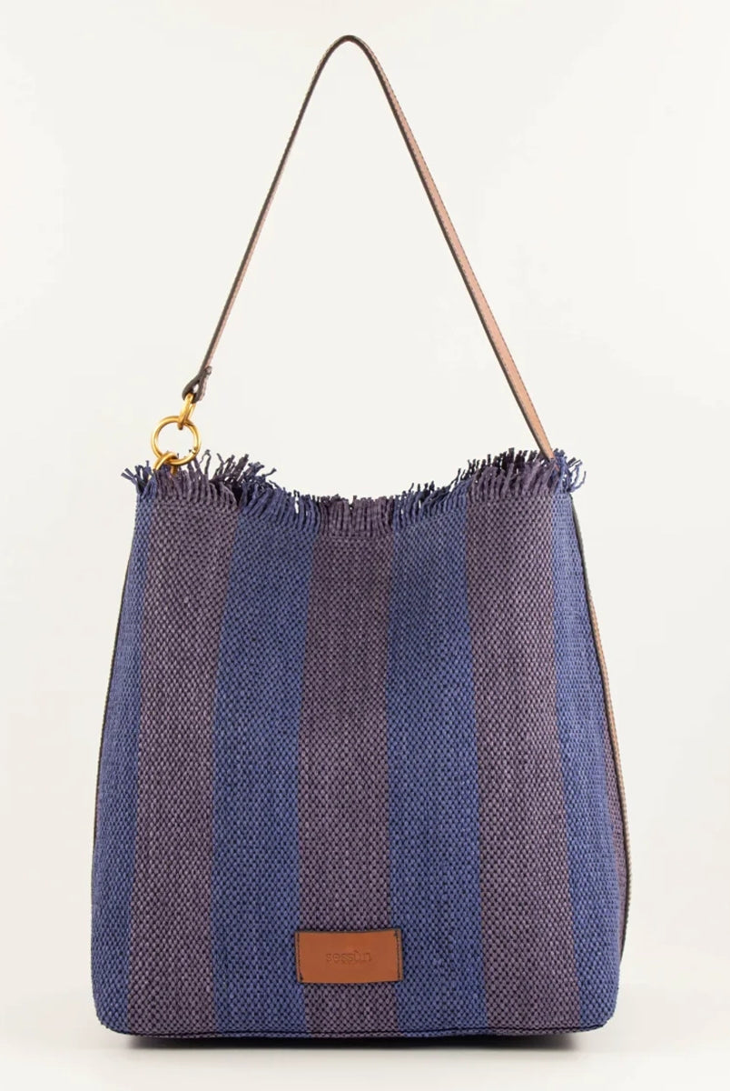Letnia, pleciona torba w pasy w typie shopper Vita Mia Sessun. U góry wykończona frędzlami. Torba posiada skórzany pasek do wygodnego zawieszenia na ramieniu oraz niewielką naszywkę z logo marki na froncie. Wewnątrz torebki znajduje się niewielka, zapinana na zamek błyskawiczny kieszonka na najważniejsze drobiazgi.