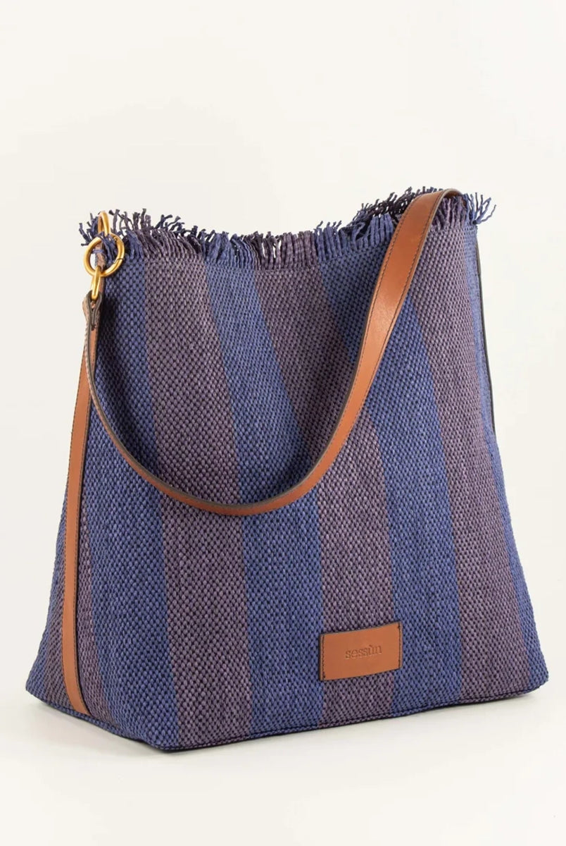 Letnia, pleciona torba w pasy w typie shopper Vita Mia Sessun. U góry wykończona frędzlami. Torba posiada skórzany pasek do wygodnego zawieszenia na ramieniu oraz niewielką naszywkę z logo marki na froncie. Wewnątrz torebki znajduje się niewielka, zapinana na zamek błyskawiczny kieszonka na najważniejsze drobiazgi.