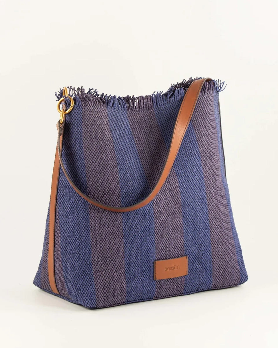 Letnia, pleciona torba w pasy w typie shopper Vita Mia Sessun. U góry wykończona frędzlami. Torba posiada skórzany pasek do wygodnego zawieszenia na ramieniu oraz niewielką naszywkę z logo marki na froncie. Wewnątrz torebki znajduje się niewielka, zapinana na zamek błyskawiczny kieszonka na najważniejsze drobiazgi.