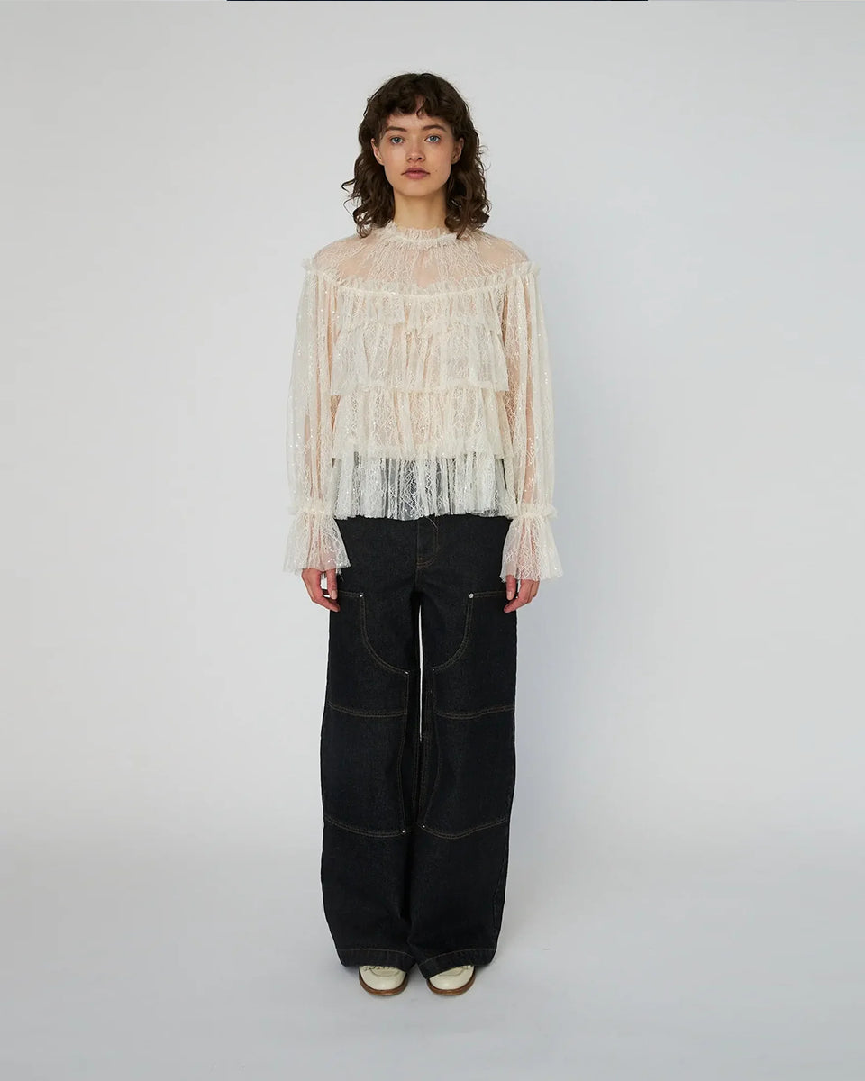 Lekka, koronkowa bluzka Sheer Frill Lace marki STELLA NOVA z długimi rękawami i falbankami na korpusie. Dekolt jest zapinany z tyłu na mały guzik z pętelką. Bluzka nie posiada podszewki. 