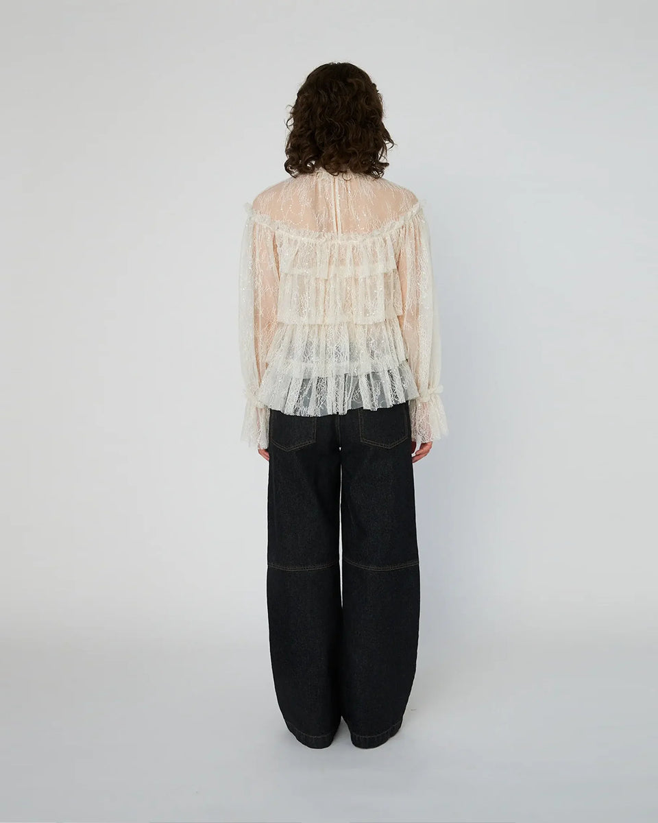 Lekka, koronkowa bluzka Sheer Frill Lace marki STELLA NOVA z długimi rękawami i falbankami na korpusie. Dekolt jest zapinany z tyłu na mały guzik z pętelką. Bluzka nie posiada podszewki. 